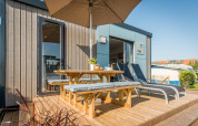 Terrasse en bois avec table de pique-nique, bancs et chaises longues au Holiday Village Knokke en Belgique.