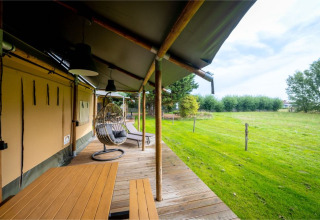 Tenda safari 'Nomad Family' a Holiday Village Knokke, Belgio, con veranda coperta e vista sul prato verde.