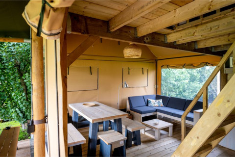 Interior de la tienda safari 'Nomad Family' en Holiday Village Knokke, Bélgica, con muebles de madera y sofás.