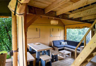 Interiør af safaritelten 'Nomad Family' i Holiday Village Knokke, Belgien, med træmøbler og loungehjørne.