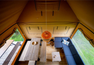 Udsigt over interiøret i Nomad Family safari-teltet med sofa, spisebord og opholdsområde i Knokke, Belgien.