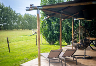 Außenbereich des Safari-Zeltes „Nomad Family“ im Holiday Village Knokke, Belgien, mit Liegestühlen und Hängesessel.