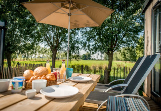Frühstück im Freien auf der Terrasse im Holiday Village Knokke mit Sonnenschirm und Feldblick.