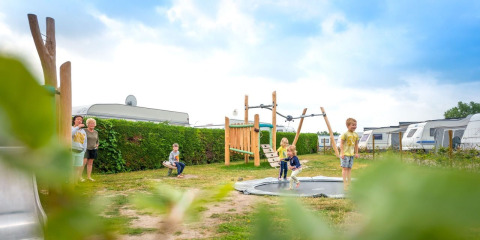 Niños jugando en un parque infantil cerca de caravanas en Holiday Village Knokke, Flandes Occidental, Bélgica.