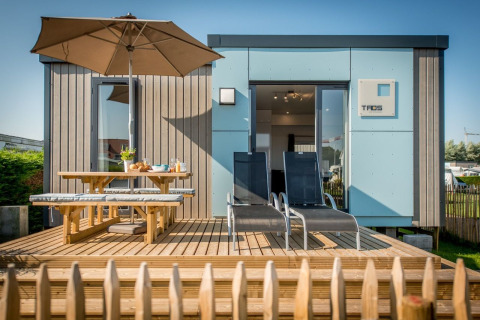 Vakantiehuis met houten terras, parasol, picknickbank en ligstoelen in Holiday Village Knokke, West-Vlaanderen.