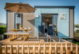 Cabane de vacances avec terrasse en bois, parasol, banc et transats à Holiday Village Knokke, Belgique.