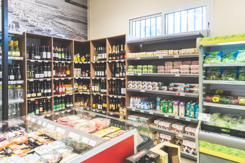 Minimarket del campeggio Spina Family Collection con vini, latticini e verdure fresche sugli scaffali.
