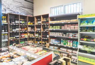 Minimarket del campeggio Spina Family Collection con vini, latticini e verdure fresche sugli scaffali.