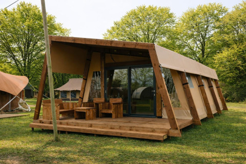 Safari tent Tribe lodgetent with private sanitary facilities, set in a green, wooded landscape.