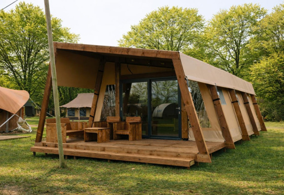 Tenda safari Tribe lodgetent con servizi igienici privati, situata in un ambiente verde e boscoso.