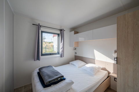 Bedroom at Cottage Prestige in Campsite Seasonova Les Portes d'Alsace, France, with double bed and window.