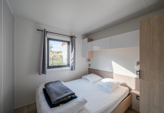 Bedroom at Cottage Prestige in Campsite Seasonova Les Portes d'Alsace, France, with double bed and window.