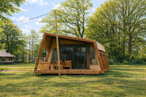 Safari-teltet Tribe lodgetent på Holiday park Mölke i Holland, omgivet af grønne træer og natur.