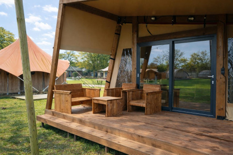 Terrasse en bois avec meubles rustiques devant la Tribe lodgetent au parc Mölke, aux Pays-Bas