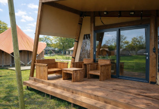 Terrazza in legno con mobili rustici davanti al Tribe lodgetent al parco vacanze Mölke, nei Paesi Bassi