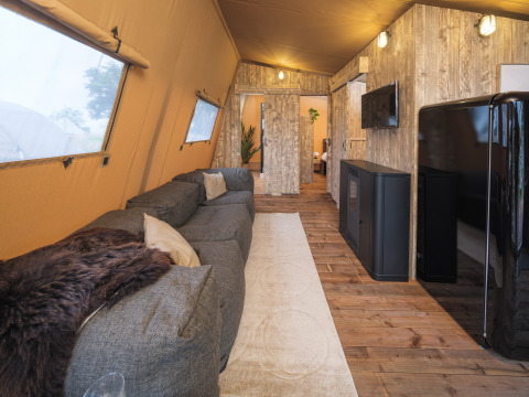 Indretning af en Tribe lodgetelt i Holiday park Mölke, Holland, med sofa, tæppe og rustik indretning.