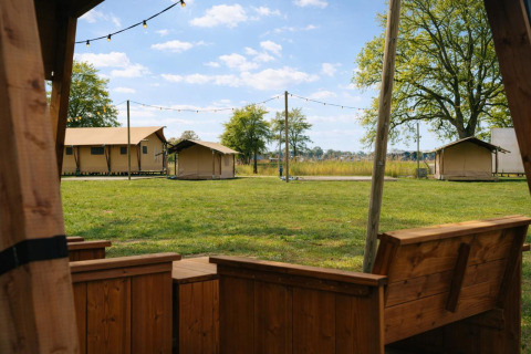 Udsigt fra en træterrasse mod Tribe lodgetelte og grønne områder i Holiday park Mölke, Holland.