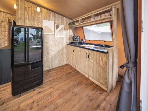 Moderne køkkeninteriør i Tribe lodgetelt ved Holiday park Mölke, Holland, med træpaneler og sort køleskab.