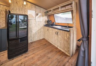 Moderne køkkeninteriør i Tribe lodgetelt ved Holiday park Mölke, Holland, med træpaneler og sort køleskab.