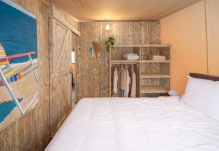 Camera nella Tribe lodgetent all'Holiday park Mölke, Paesi Bassi, con letto rustico e armadio in legno.