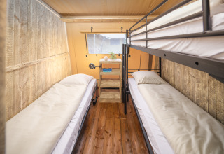 Indvendig af Tribe lodgetelt ved Holiday park Mölke, Nederlandene, med køjesenge og trævægge.