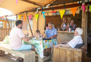 Familie nyder et måltid sammen i en luksus safaritelte på campingpladsen 't Veld i Holland.