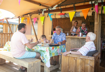 Family sharing a meal in the Safari tent “de luxe” at Campsite 't Veld in the Netherlands, decorated festively.