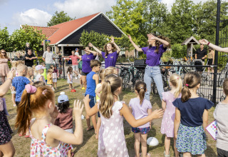 Niños bailan y juegan al aire libre junto a una tienda safari en el camping 't Veld en los Países Bajos.