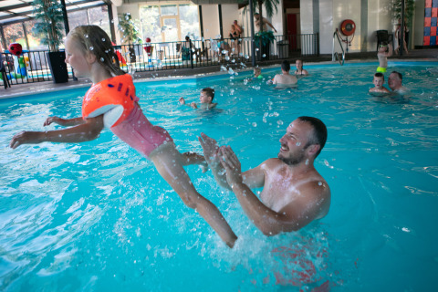Un hombre juega con una niña en una piscina cubierta del Safari tent de luxe en el Camping 't Veld, Países Bajos.