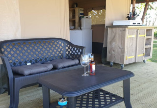 Outdoor seating area in Safari tent at Campsite Eefting in the Netherlands, with sofa, table and kitchenette.