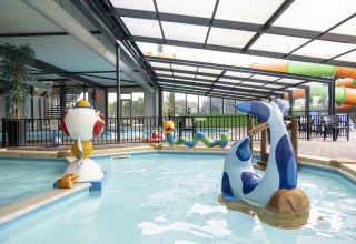 Piscina cubierta con juguetes acuáticos y toboganes en un alojamiento de glamping ideal para familias.