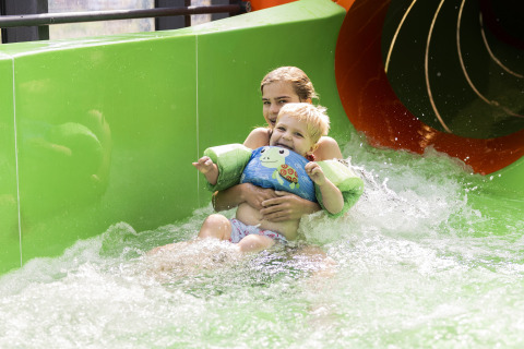 Two kids in floaties having fun on a water slide at Beach house with hottub at Campsite 't Veld, Netherlands.