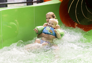 Two kids in floaties having fun on a water slide at Beach house with hottub at Campsite 't Veld, Netherlands.