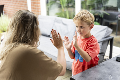 Een vrouw en een jongen spelen handjeklap in een safaritent op camping 't Veld in Nederland.