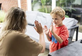 Een vrouw en een jongen spelen handjeklap in een safaritent op camping 't Veld in Nederland.