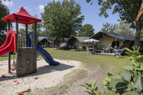 Parque infantil y tiendas safari Comfort en el camping 't Veld en Países Bajos, familias disfrutando.
