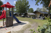 Spielplatz mit Rutsche und komfortablen Safarizelten auf dem Campingplatz 't Veld in den Niederlanden.