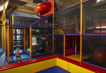 Indoor playground with colorful climbing structures and a child at Comfort safari tent at Campsite 't Veld.