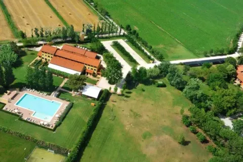 Aerial view of Dune Agriturismo holiday park in Veneto, Italy, featuring pool, fields, and buildings.