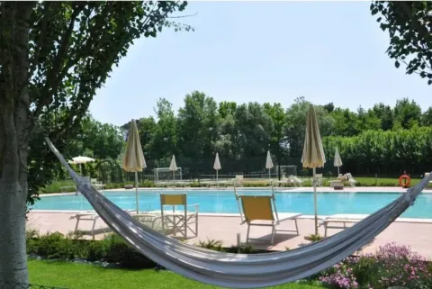 Hamac avec vue sur la piscine, transats et parasols au Dune Agriturismo, parc de vacances en Vénétie, Italie.