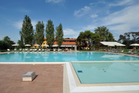 Piscina all'aperto con lettini e ombrelloni al Dune Agriturismo, parco vacanze in Veneto, Italia.