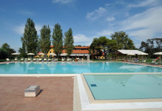 Piscina all'aperto con lettini e ombrelloni al Dune Agriturismo, parco vacanze in Veneto, Italia.