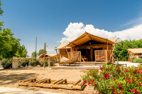 Luxury glamping tent at Dune Agriturismo holiday park in Veneto, Italy, with sunny skies and vibrant flowers.