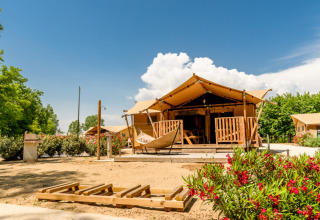 Tienda glamping de lujo en Dune Agriturismo, parque vacacional en Véneto, Italia, con flores y cielo soleado.