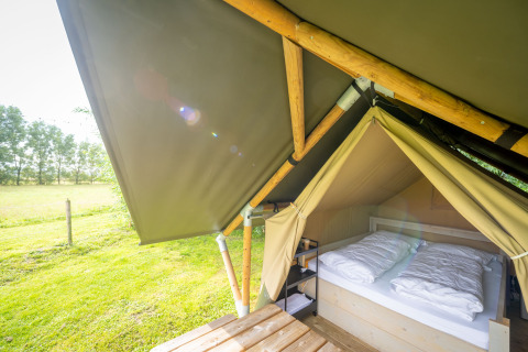 Safari-tent Nomad Double bij Holiday Village Knokke in België, met tweepersoonsbed en uitzicht op grasveld.