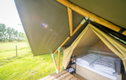Nomad Double safari tent at Holiday Village Knokke, Belgium, featuring a double bed and green outdoor view.