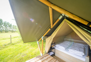 Safari-tent Nomad Double bij Holiday Village Knokke in België, met tweepersoonsbed en uitzicht op grasveld.