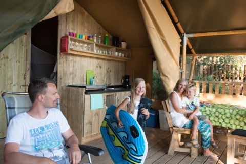 Famille profitant d’un moment ensemble dans une tente safari au camping Rosselba le Palme, en Italie.