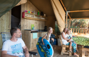 Familia disfrutando junta en una tienda safari en el Camping Rosselba le Palme en Italia.