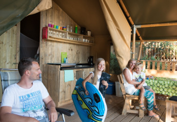 Family relaxing together at a safari tent at Campsite Rosselba le Palme in Italy, enjoying the outdoors.